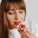 Woman with long hair savoring a gourmet canape indoors.